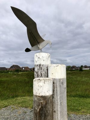 Skulptur einer Möwe aus Eisen in Friedrichskoog Spitze mit Häusern im Hintegrund