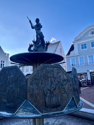 Georgsbrunnen auf dem Marktplatz in Heide mit Figur und Reliefs zur Geschichte Dithmarschens